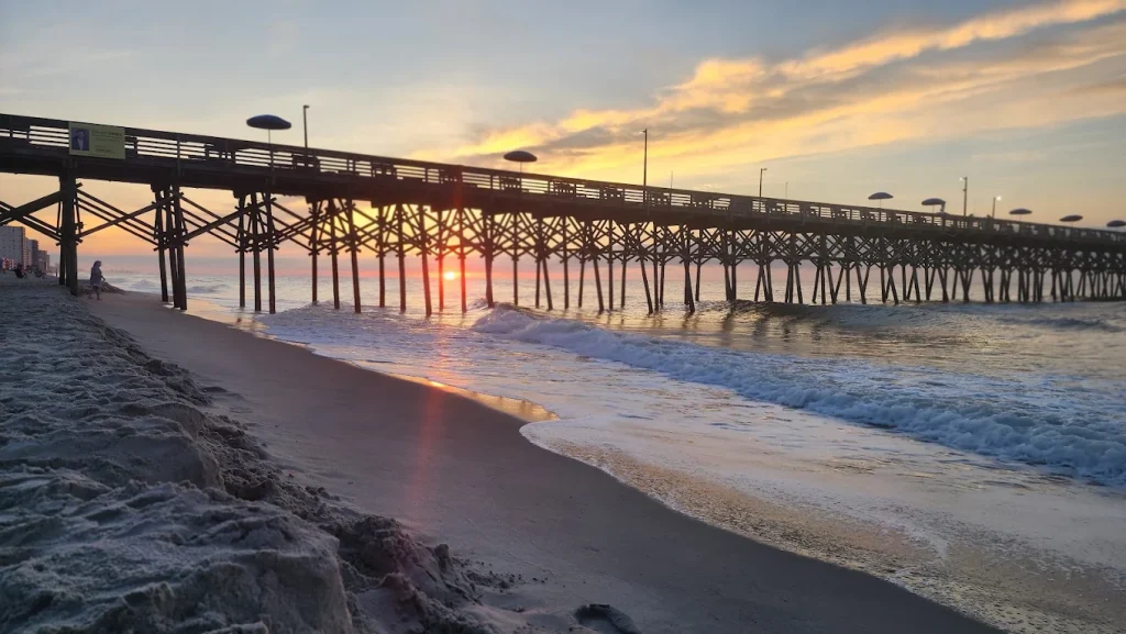 Garden City Pier extending 668 feet into Atlantic Ocean at Garden City Beach South Carolina with fishing anglers and covered shelter at end